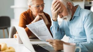 An older couple looking over paperwork with looks of stress and disappointment.